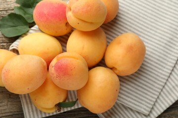 Fresh apricots and green leaves on wooden table, flat lay
