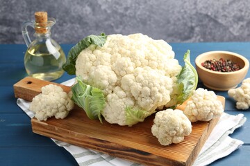 Raw cauliflower, peppercorns and oil on blue wooden table