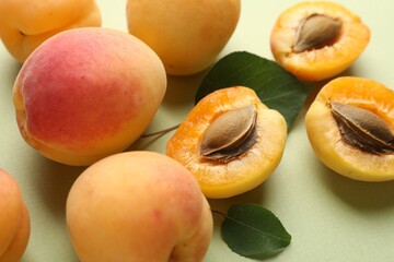 Fresh ripe apricots and leaves on pale green background, closeup