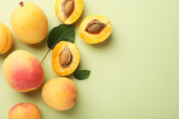 Fresh ripe apricots and leaves on pale green background, flat lay. Space for text