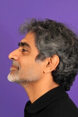 Fototapeta premium A studio shot capturing the essence of a modern man. Conceptual art of style for aging men. Purple solid background. Modish men's two-block cut haircut - midlife indian man with curly hair.