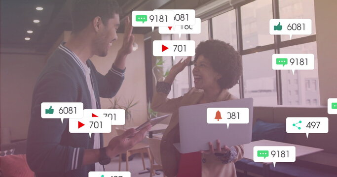 High-fiving colleagues in office lounge with tablet smartphone notification icon overlays