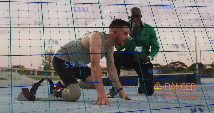 Crouching amputee runner using blade at blocks on track, with coach using device overlaying danger - Powered by Adobe