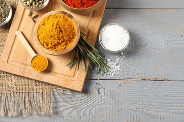 Different aromatic spices on grey wooden table, flat lay. Space for text