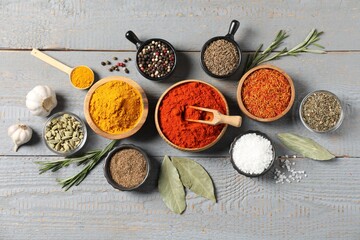 Different aromatic spices on grey wooden table, flat lay