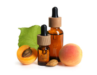 Bottles of essential oil, fresh apricots, kernels and green leaf isolated on white