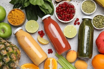 Superfood. Tasty smoothies in glass bottles and ingredients on light grey table, flat lay