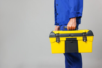 Professional repairman with tool box on grey background, closeup. Space for text