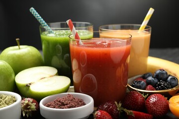 Superfood. Refreshing smoothies in glasses and ingredients on dark table, closeup