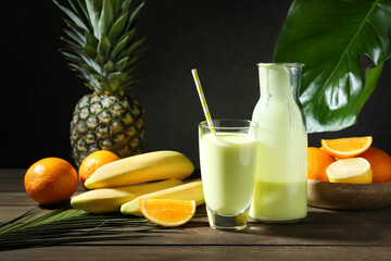 Superfood. Refreshing smoothie in bottle, glass, palm leaf and ingredients on wooden table against...