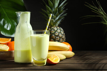 Superfood. Refreshing smoothie in bottle, glass and ingredients on wooden table against black...
