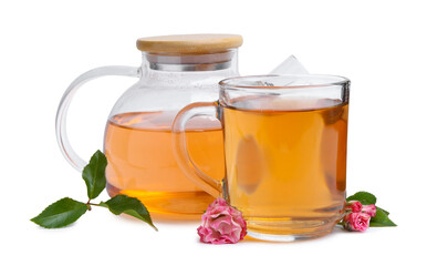 Aromatic tea in glass cup, teapot, roses and green leaves isolated on white