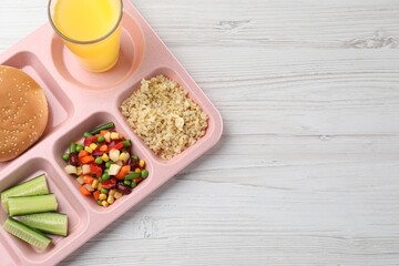 School lunch. Plastic tray with tasty food and orange juice on light wooden table, top view. Space for text