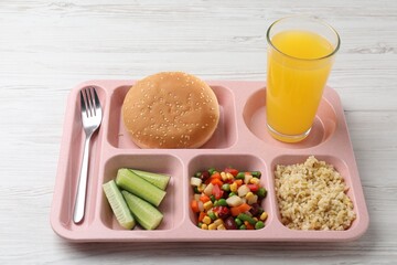 Plastic tray with tasty food, orange juice and fork on light wooden table, closeup. School lunch