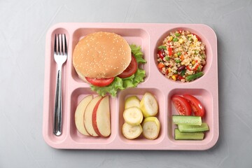 Plastic tray with tasty food and fork on grey table, top view. School lunch