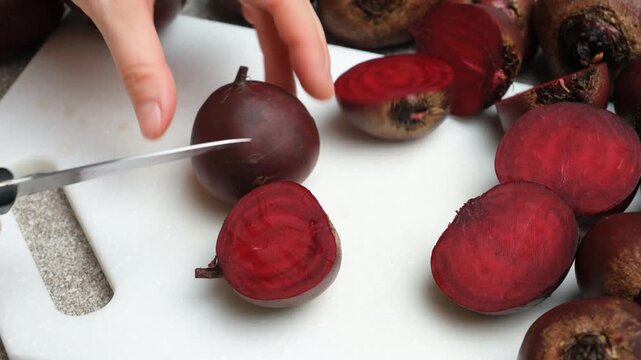 Hands cutting fresh raw red beets beetroot in half
