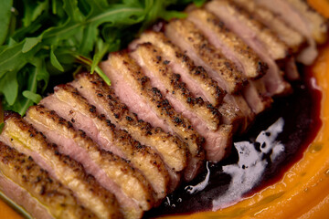 Deliciously Sliced Duck Breast Served on a Plate with Fresh Arugula and Rich Sauce for a Gourmet Culinary Experience