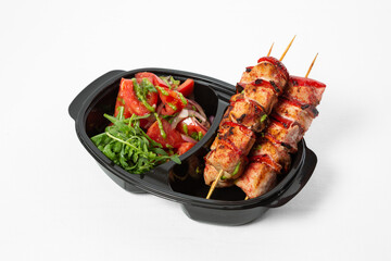 Chicken barbecue on a skewer with vegetables on a plate on a white background