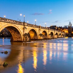 Obraz premium Stone bridge over calm river at twilight