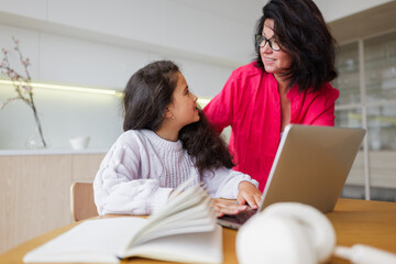 Woman and girl share a joyful learning moment at the table