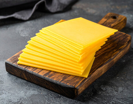 Stack of Processed Cheese Slices on Rustic Wooden Cutting Board, Dark Background