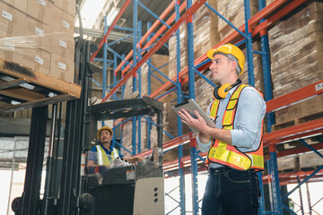 Smart caucasian warehouse man,manager use digital tablet check package with worker forklift driver...