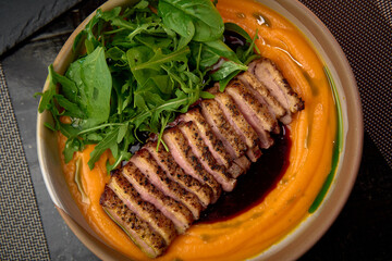 Deliciously Plated Duck Breast Served Over Creamy Sweet Potato Purée with Fresh Greens and Rich Sauce for a Savory Culinary Delight