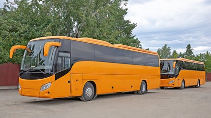 Modern gray and yellow tour buses arranged neatly in a parking lot against a backdrop of rolling hills and greenery