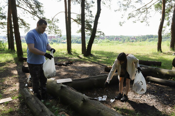 Family doing community service in nature, dad and teen daughter collecting waste, forest restoration effort, positive parenting and environmental activism through shared tasks.