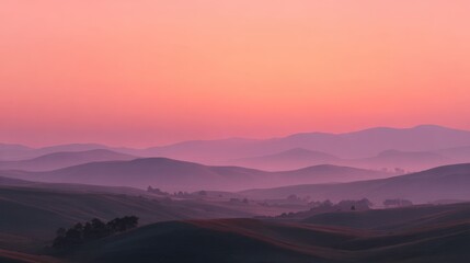 Misty hills bathed in a soft, pink sunrise
