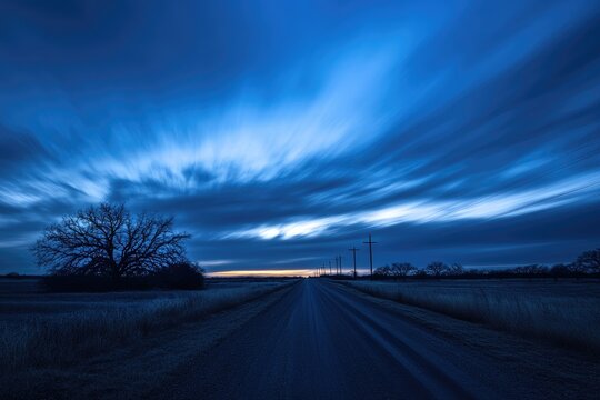 A country road stretches into a vibrant twilight sky