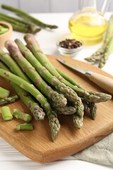 Fresh raw asparagus spears and knife on white wooden table, closeup