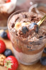 Taking delicious chocolate pudding with chia seeds and blueberries from glass on table, closeup
