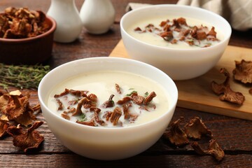 Tasty cream soup with mushrooms and thyme in bowl on wooden table, closeup