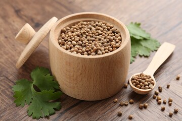Fresh cilantro and coriander seeds on wooden table, closeup