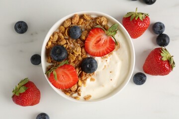 Tasty yogurt with granola and berries on white marble table, flat lay