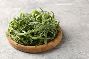 Fresh ripe green arugula leaves on grey table, closeup