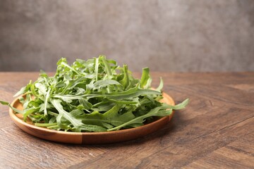 Fresh ripe green arugula leaves on wooden table, closeup. Space for text