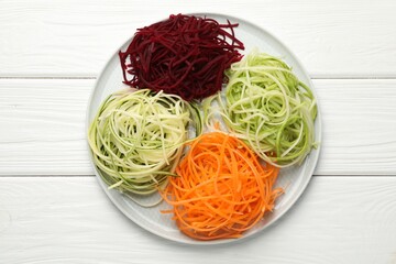 Different vegetable noodles on white wooden table, top view. Vegetarian dish