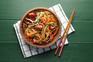Tasty vegetable noodles served on green wooden table, top view