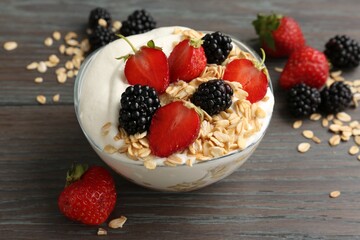Tasty yogurt with granola and berries in bowl on wooden table, closeup