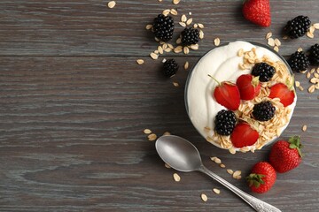 Tasty yogurt with granola and berries in bowl on wooden table, flat lay. Space for text