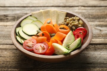 Healthy vegetarian food. Delicious Buddha bowl with lentils, tofu and vegetables on wooden table, closeup