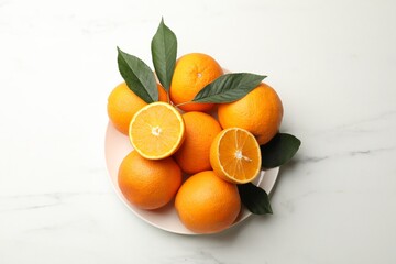 Fresh oranges and leaves on white marble table, top view