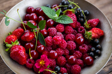  Different types of berries raspberry, strawberry, cherry and currant in a bowl close up