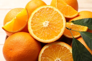 Fresh ripe oranges and leaves on light table, closeup