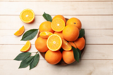 Fresh ripe oranges and leaves on light wooden table, flat lay. Space for text