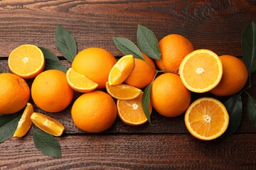 Fresh ripe oranges and leaves on wooden table, flat lay