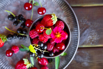  Different types of berries on a black wooden background. Raspberry, strawberry, cherry and currant