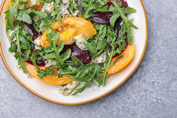 Tasty salad with arugula, blue cheese and vegetables on grey textured table, top view